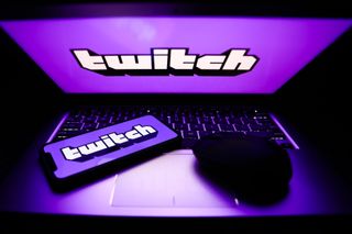 A laptop and phone displaying the Twitch logo.